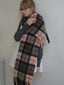 Woman in a grey sweater and white dress, wearing a large plaid scarf.