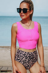 Woman wearing a bright pink cropped tankini top with leopard print high-waisted bottoms on a beach