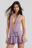 Woman wearing a lavender denim halter mini dress with a plunging neckline and a pleated skirt.