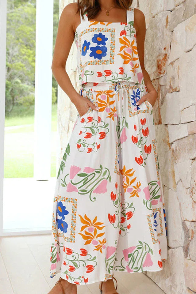 Back view of a woman wearing a white floral print two-piece set with a cropped top and wide-leg pants.