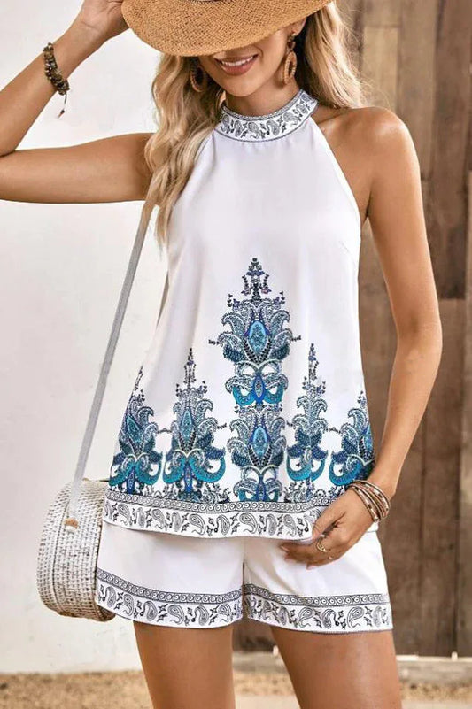 Woman wearing a white halter top with blue paisley print and matching white shorts with blue paisley print trim.