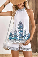 Woman wearing a white halter top with blue paisley print and matching white shorts with blue paisley print trim.