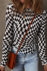 Close-up front view of a woman wearing a black and white checkerboard long-sleeved mesh top, blue jeans, and a brown crossbody bag.
