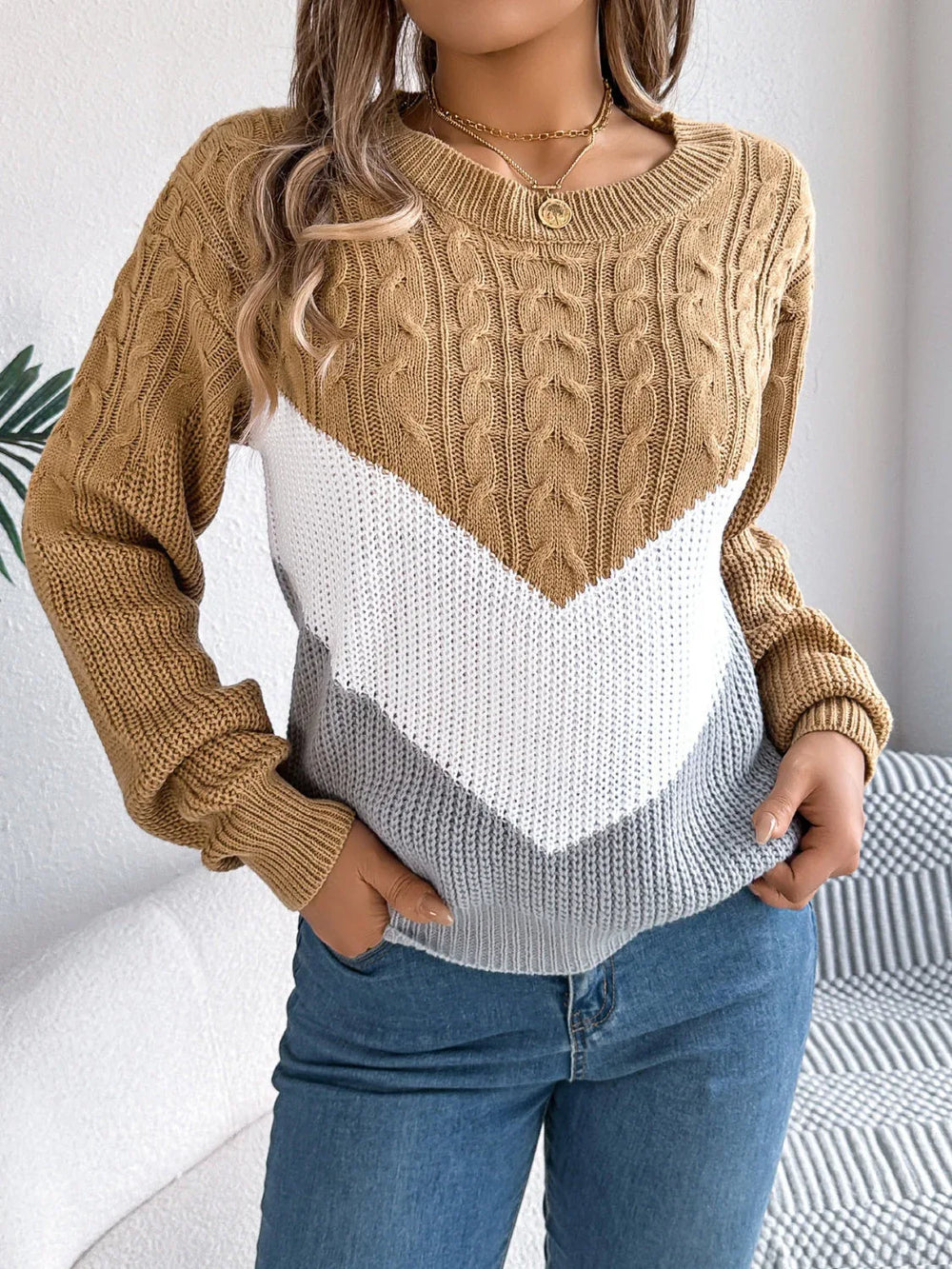 Woman wearing a brown, white, and grey colorblock chevron knit sweater with blue jeans