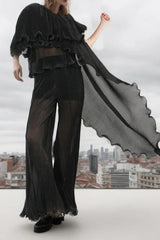 woman wearing a black pleated ruffled top and wide-leg pants