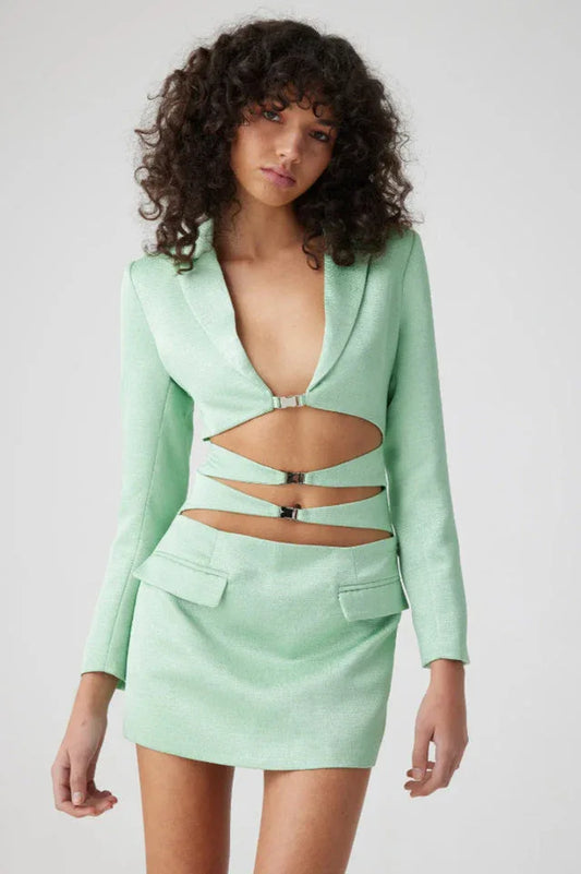 Model wearing a mint green cut-out blazer and mini skirt set.