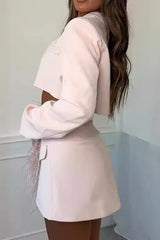 Back view of a woman wearing a pink cropped blazer and asymmetrical skirt with feather trim