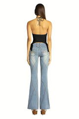 Back view of a woman wearing a black halter top and light wash flared jeans.