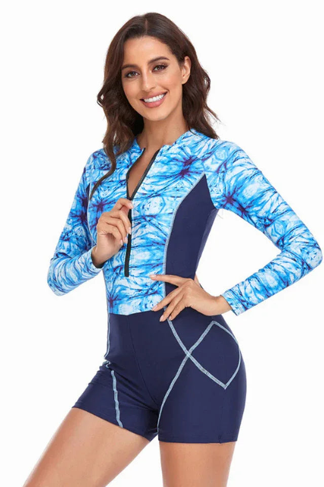 Woman wearing a blue tie-dye long-sleeve one-piece swimsuit with shorts, front view