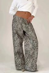 Close-up of a model wearing wide leg leopard print denim pants and a white crop top, hands on hips.