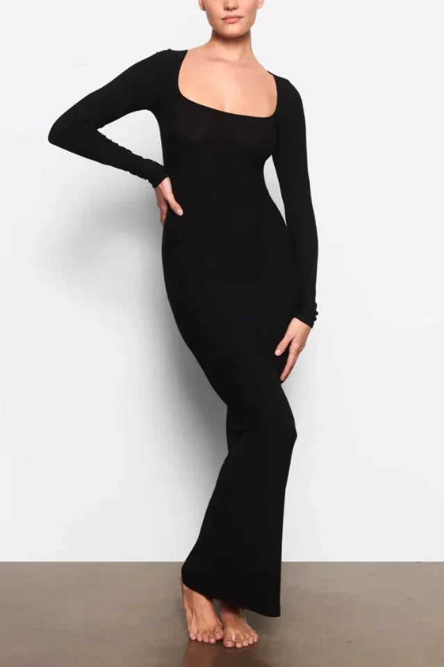 Woman wearing a long-sleeved, ribbed knit, square-neck, black maxi dress, front view.