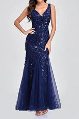 Woman wearing a floor-length navy blue sequined mermaid gown with a V-neckline and sleeveless design.