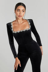 Close-up of the embellished neckline of a black velvet jumpsuit.