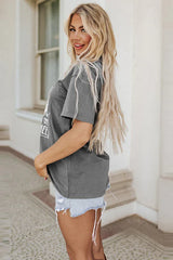 Side view of a woman in a grey graphic t-shirt and denim shorts.