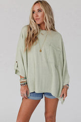 Woman from the side wearing a light green ribbed top with cuffed sleeves and denim shorts.