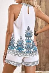 Back view of a woman in a white halter top with blue paisley print and matching white shorts.
