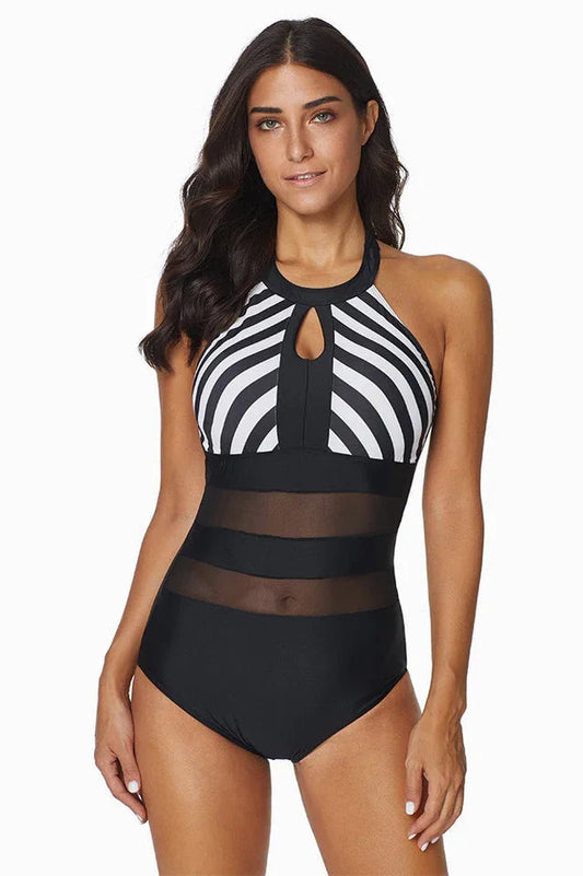 Woman wearing a black and white striped halter one-piece swimsuit with sheer mesh panels