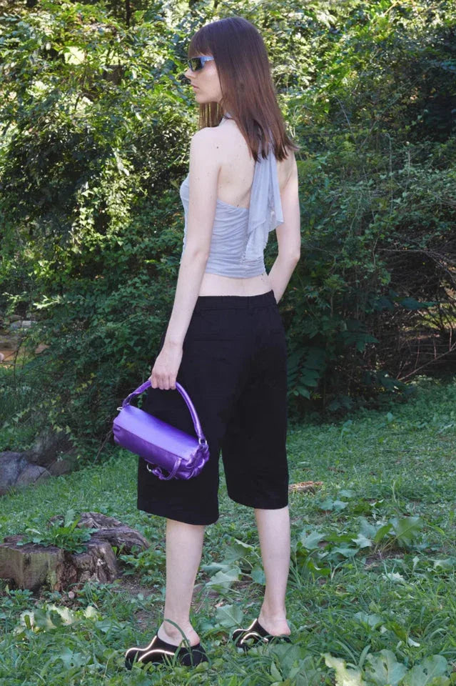 woman from behind wearing a light blue ruched halter top and black shorts outdoors