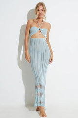 Woman wearing a light blue knit maxi dress with a halter neckline and cut-out detail, standing against a white backdrop.