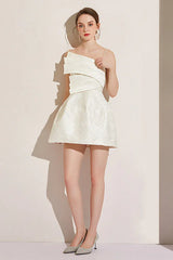 Full body shot of a woman in a white asymmetrical neckline dress with a short A-line skirt.