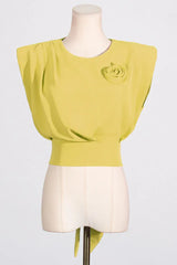 Close-up of a yellow cropped top with a rose embellishment and draped detailing, displayed on a mannequin.