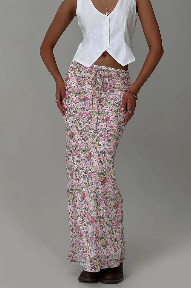 Close-up of a woman's torso and legs wearing a white cropped vest and a floral print maxi skirt.