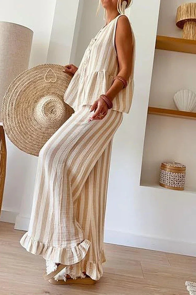 Side view of a woman in a striped linen blend outfit with a peplum top and wide leg pants.