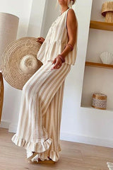 Side view of a woman in a striped linen blend outfit with a peplum top and wide leg pants.