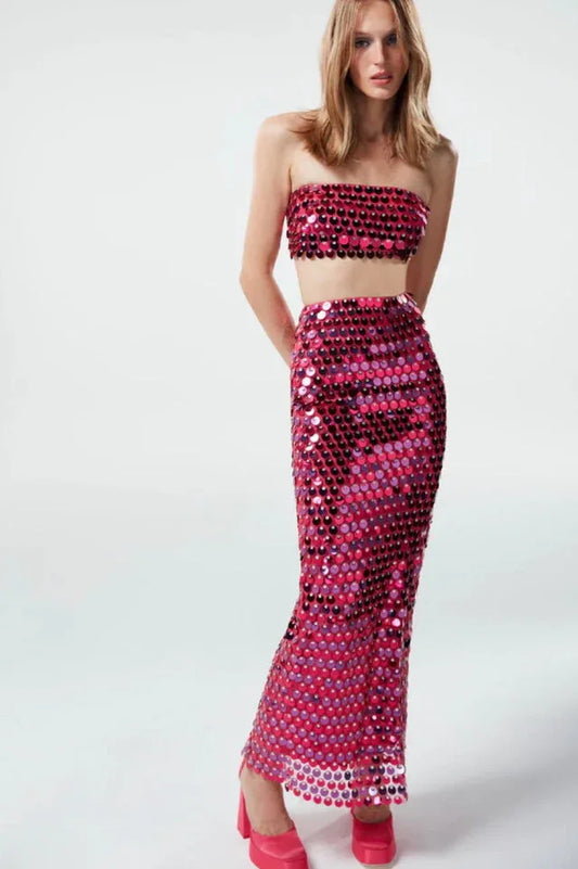 Model wearing a pink sequined strapless top and matching full-length skirt against a white background.
