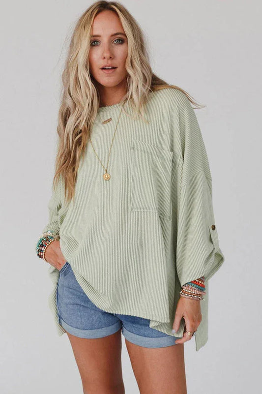 Woman wearing a light green ribbed long-sleeve top with a chest pocket and denim shorts.