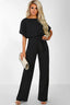 Woman wearing a black wide leg jumpsuit with a tie waist and boat neck
