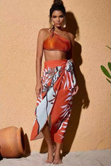 Woman wearing an orange one-shoulder bikini top and a matching sarong