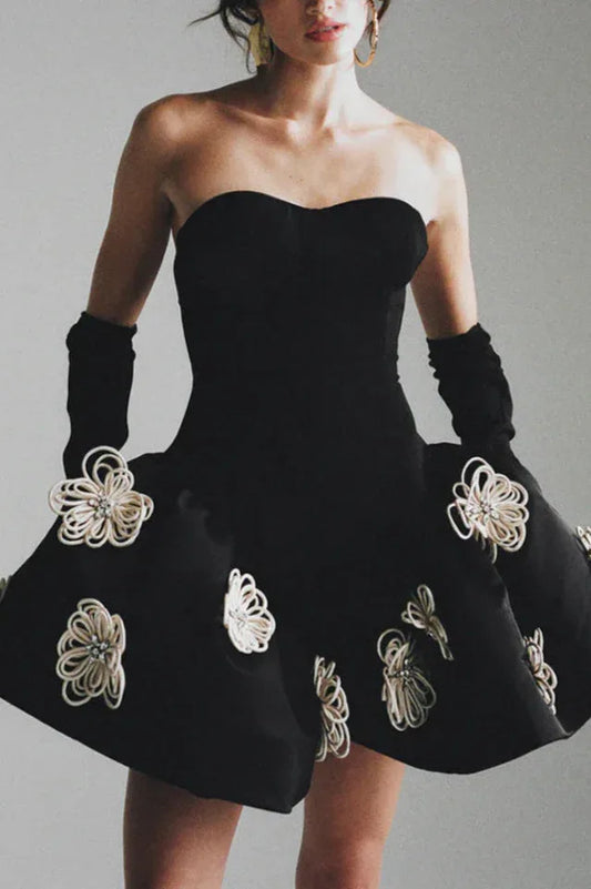 Woman wearing a black strapless cocktail dress with white floral appliqués and long black gloves