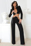 Woman wearing a black cropped blazer with a plunging neckline and cut-out pants with a chain detail.