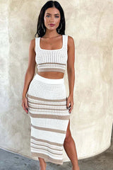 Woman wearing a white and tan striped knit cropped tank top and matching midi skirt with a side slit, slightly angled front view