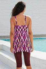 Woman wearing a purple, pink, and yellow abstract print tankini with burgundy capri leggings by a pool, showing the back.