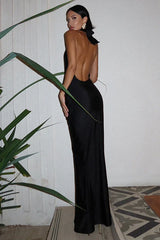 Back view of a woman in a long black satin halter dress with an open back.