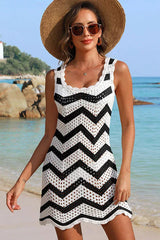 Woman wearing a black and white chevron crochet knit mini dress with a straw hat and sunglasses on a beach.