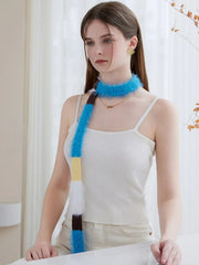 Model wearing a white ribbed tank top and off-white pants, with a fluffy, color-blocked scarf wrapped once around her neck.