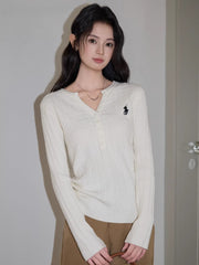 Full-body shot of a woman standing, showcasing the white cable knit henley sweater and brown wide-leg pants.