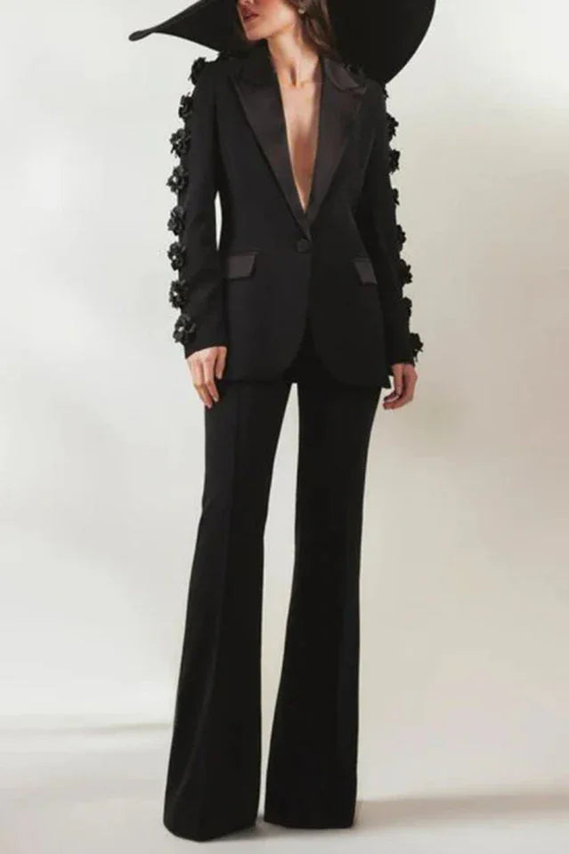 Woman posing in a black formal suit with dramatic floral sleeve details