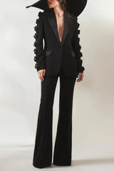 Woman posing in a black formal suit with dramatic floral sleeve details