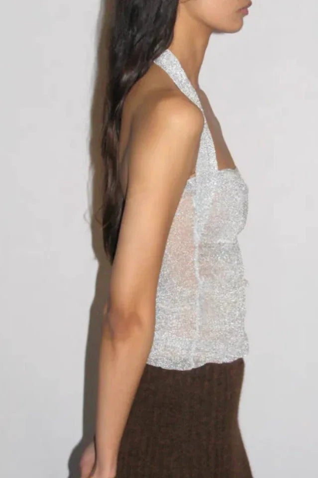 Side view of a model in a silver sparkly halter top and a brown knit maxi skirt.