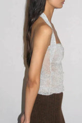 Side view of a model in a silver sparkly halter top and a brown knit maxi skirt.