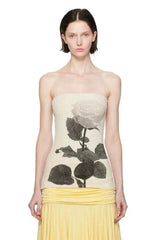 Woman wearing a cream strapless tube top with a black rose graphic print, paired with a yellow skirt.