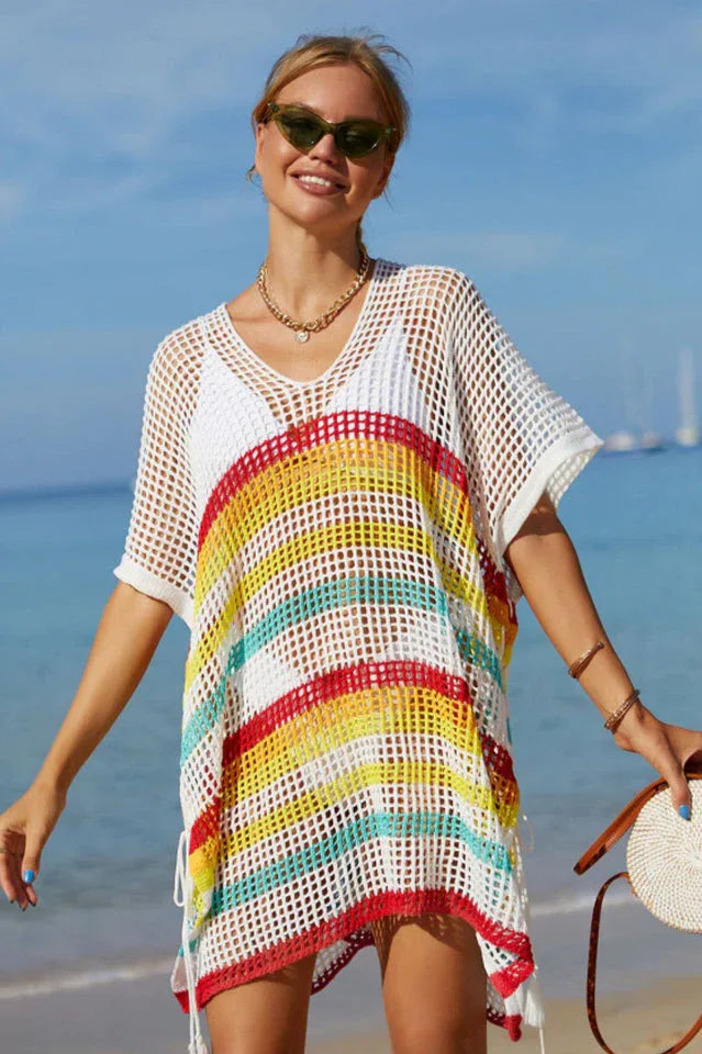 Woman wearing a white crochet knit kaftan with rainbow stripes at the beach