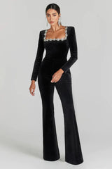 Woman wearing a black velvet jumpsuit with a square neckline and flared legs. The neckline is embellished with rhinestones.