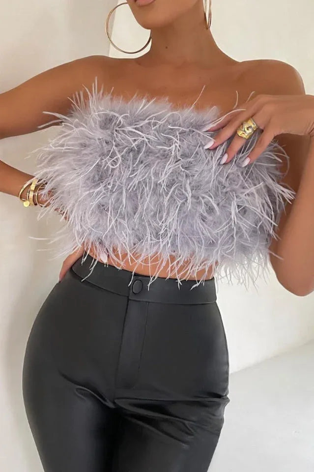 Close-up of a woman in a grey strapless feather crop top and black pants