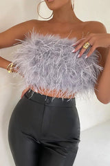 Close-up of a woman in a grey strapless feather crop top and black pants