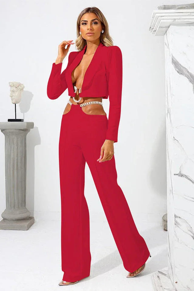 Woman wearing a red cropped blazer with a plunging neckline and cut-out pants with a chain detail.